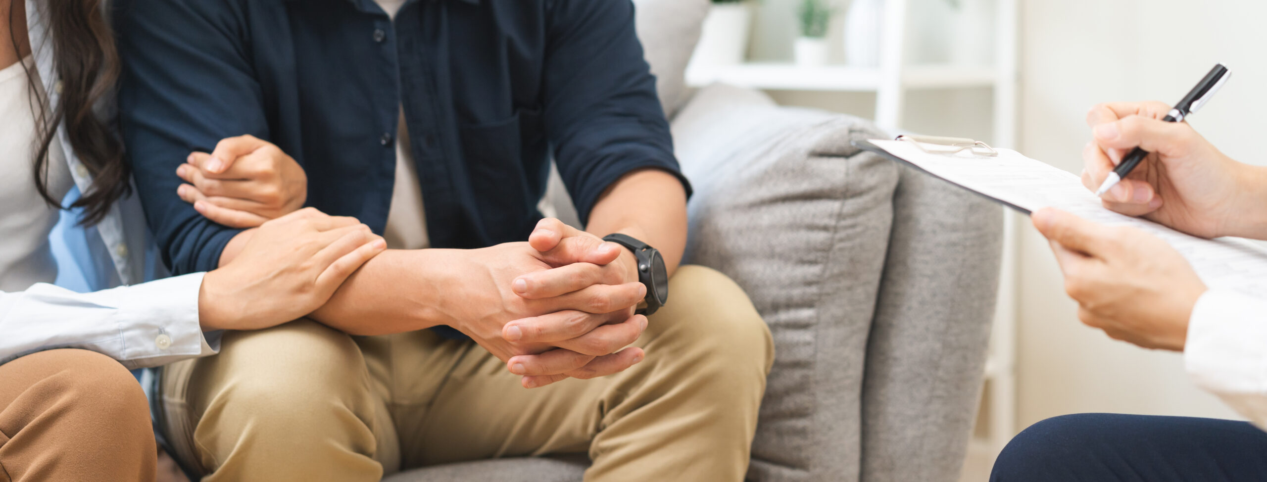 Couple sitting together during counseling session, hands intertwined, with therapist taking notes, emphasizing support and connection in therapy at The Shift Counseling and Wellness.