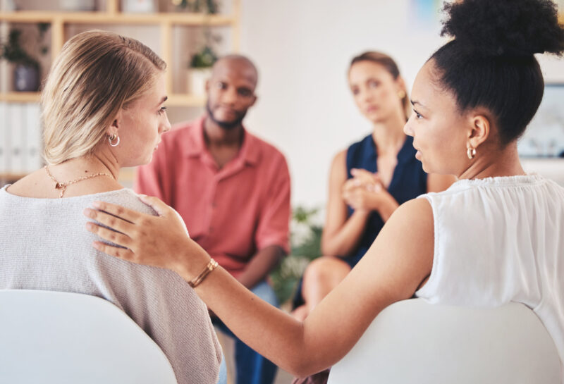 Group counseling session with diverse participants providing support and connection in a therapeutic environment.