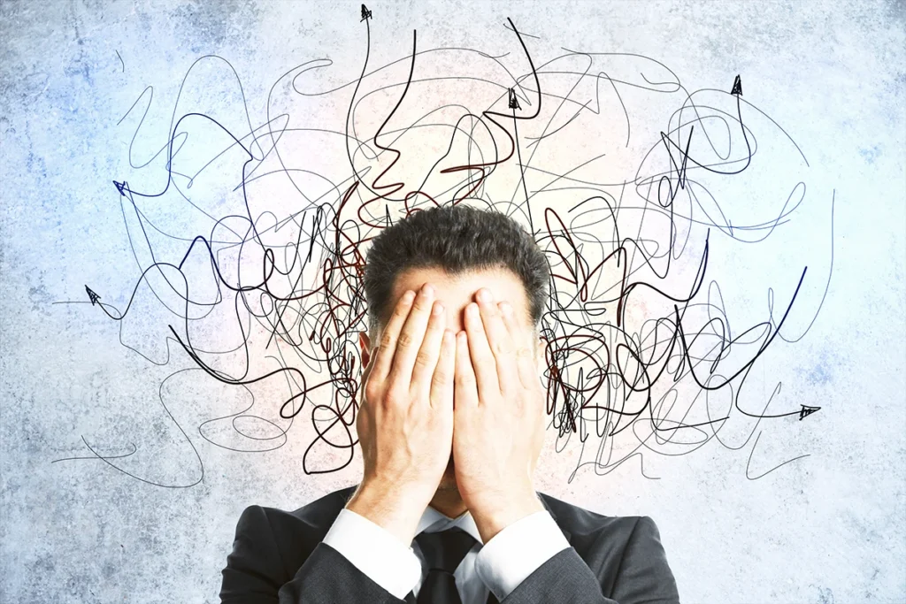 man hiding face behind hands while overwhelmed with anxiety