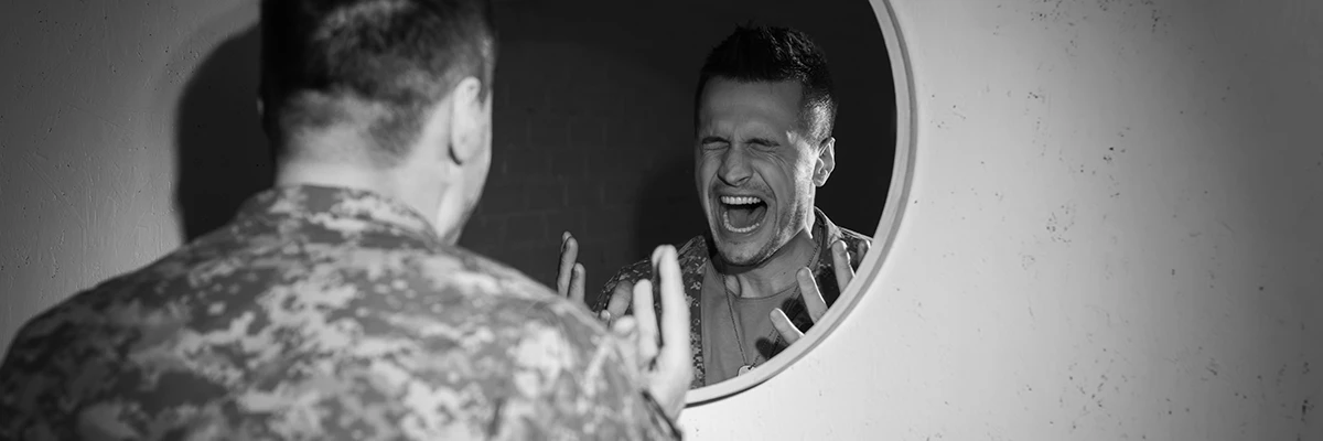 man standing at mirror screaming in anger